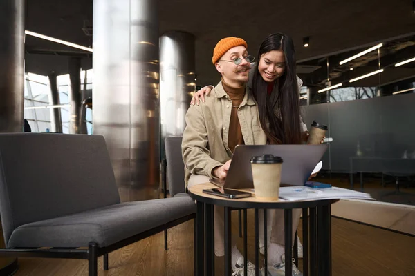 楽しいです女性オフィスワーカーとともにコーヒーカップ手抱擁彼女の幸せな同僚タイプのポータブルコンピュータ — ストック写真