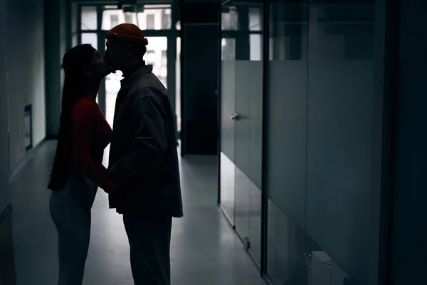 サイドビューの若いです男性接吻女性の唇に暗い廊下 — ストック写真
