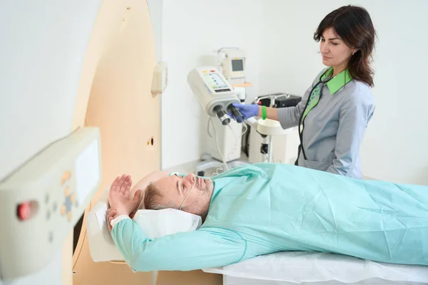 Gülümseyen Kadın Doktor Klinikte Yetişkin Bir Adamın Beyin Tomografisini Çekiyor — Stok fotoğraf