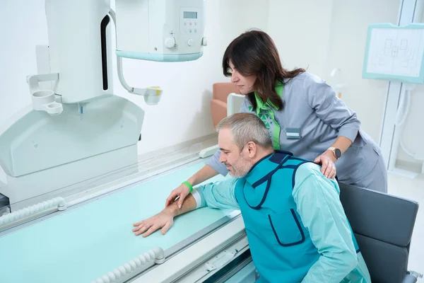 Doctora Que Muestra Hombre Cómo Sostener Mano Durante Una Radiografía — Foto de Stock