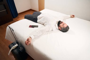 Gülümseyen zarif adam, güzel ışıklandırılmış otel odasında yatıyordu.