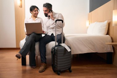 Adam telefon görüşmesi sırasında kadın arkadaşının ellerinde dizüstü bilgisayara bakıyor.