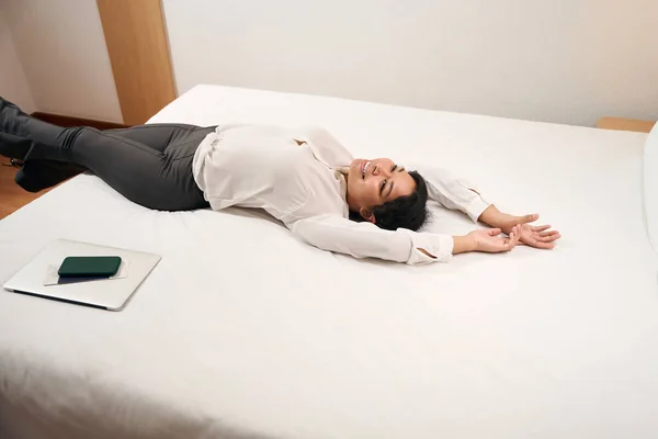 笑顔楽しい女性起業家嘘快適なベッドの上で彼女のホテルの部屋 — ストック写真