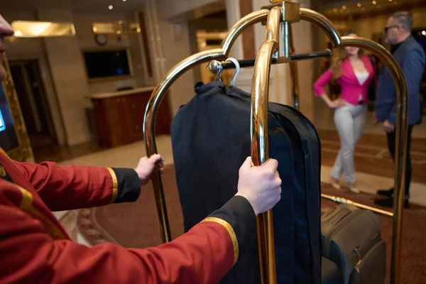 男と彼の仲間の高級ホテルのホワイエで 荷物を持ったポーターの横に立っている — ストック写真