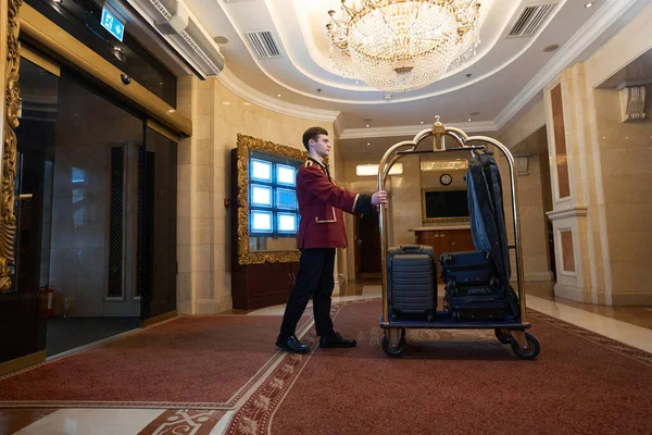 Bellhop Tradycyjnym Mundurze Niesie Wózek Bagażem Wzdłuż Holu Hotel Luksusowe — Zdjęcie stockowe