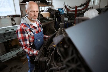 Odaklanmış orta yaşlı işçi bir araba müfrezesi kuruyor, iş elbiseli bir adam.