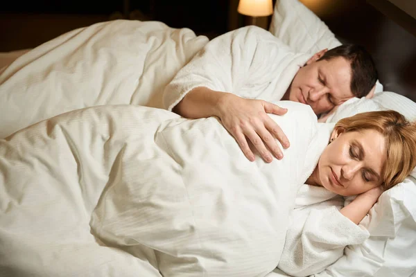 甜美的中年妇女正在柔软的枕头上小睡片刻 她的丈夫轻轻地拥抱着她 — 图库照片