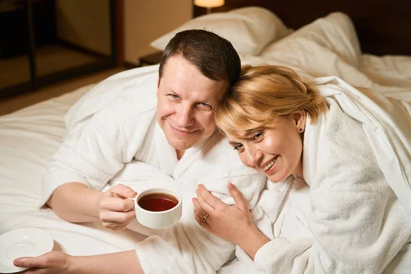 Gelukkig Paar Witte Badjassen Ontspannen Bed Man Drinken Van Zwarte — Stockfoto