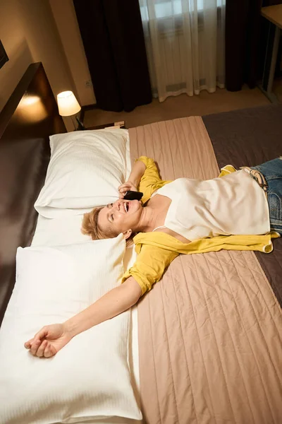 Счастливая Женщина Дорожной Одежде Лежит Большой Кровати Руки Простираются Эмоционально — стоковое фото