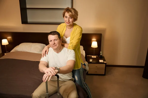 新婚夫妇入住了一家现代化舒适的旅馆 他们在旅馆房间的一张大床上坐下 — 图库照片