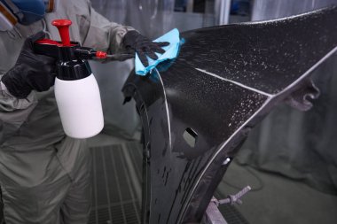 Koruyucu üniformalı dezenfekte teknisyeninin dezenfektan sprey ve bez kullanarak araba temizleme elementini kapat