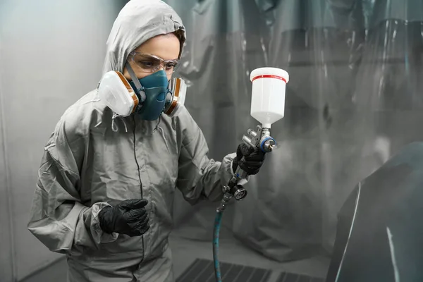 有经验的女汽车工程师 穿着防护设备 在油漆室的车体元件上工作 — 图库照片