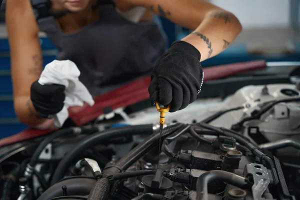 汽车修理工戴着防护手套检查汽车的油位 女人用特殊的吸盘 — 图库照片