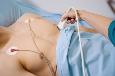 Tıbbi muayenede çıplak vücutlu bir adam, doktor kalbini kontrol ediyor.