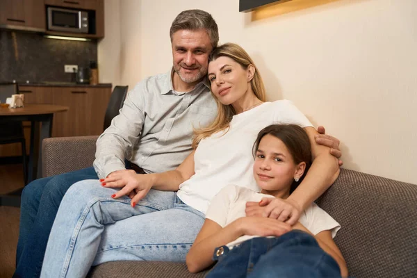 Esposa Marido Con Hija Sentado Sofá Acogedor Frente Cámara Interior —  Fotos de Stock