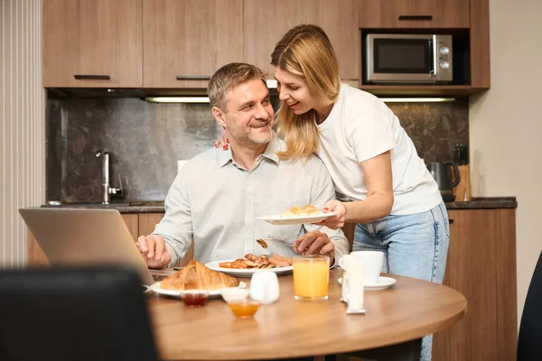 Een Lachende Man Zit Aan Tafel Keuken Kijkt Naar Een — Stockfoto
