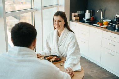 Sıcak bir ortamda, geleneksel bir kahvaltıda aşık bir çift el ele tutuşur.