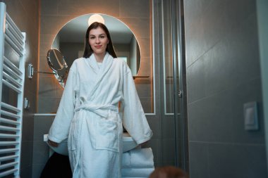 Güzel genç bir bayan banyoda duruyor, bornozlu bir kadın.