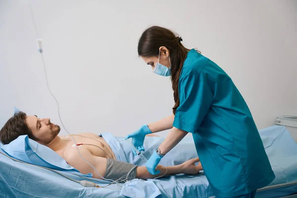 若い看護師は患者に薬を注入します 男は彼の胸に吸引カップに横たわっています — ストック写真