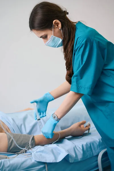 Pielęgniarka Masce Ochronnej Wstrzykuje Lek Kroplówki Mężczyzna Leży Szpitalnym Łóżku — Zdjęcie stockowe