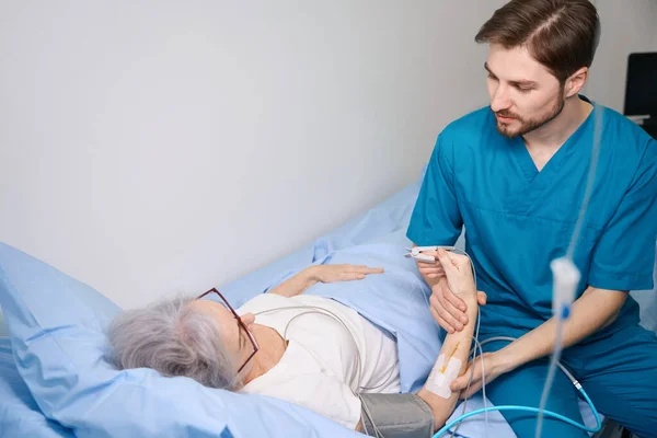 Дружня Медсестра Тримає Руку Пацієнта Лежить Ліжку Він Вимірює Пульс — стокове фото
