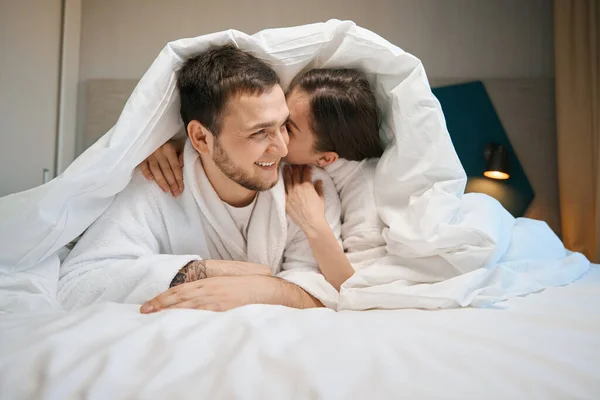 Cheerful Spouses Hug Whisper Covers Large Bed Guys Soft Bathrobes — Stock Photo, Image