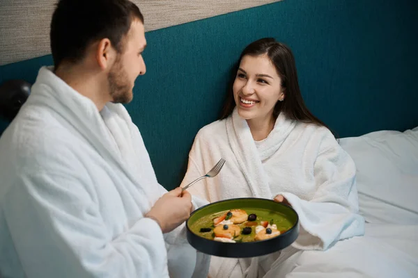 남자가 아내를 침실에서 식사를 대접하고 부부는 침대에 — 스톡 사진