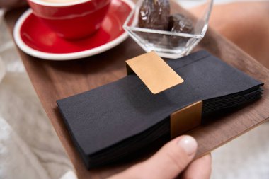 Bornozlu bir kadın bir fincan kahve ve meyve ile bir tepsi peçeteye oturur.