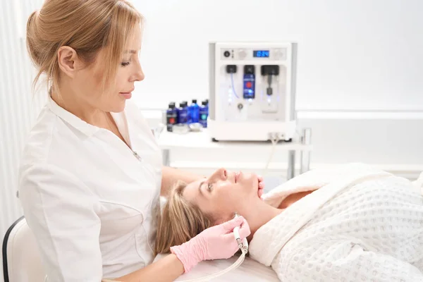 stock image Female cosmetologist works with the skin of the patients face, the specialist uses CO2 laser