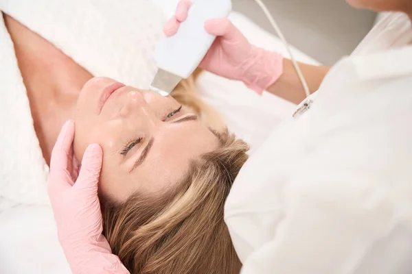 妇女在抗老化超声波洗脸过程中 专人使用超声波洗涤器 — 图库照片