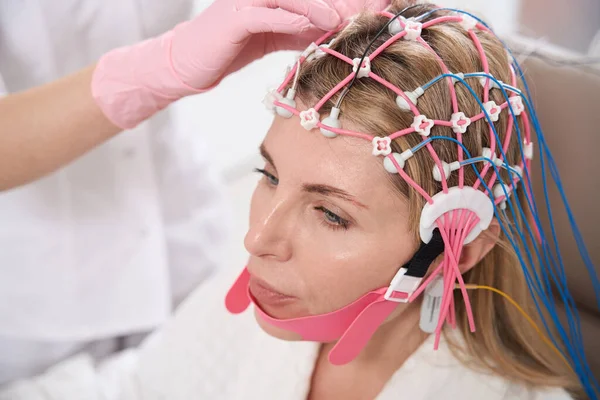 医師は 診断手順 保護手袋の診断のための女性の頭に電極とキャップを取り付けます — ストック写真