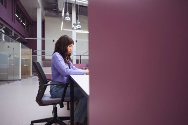 Moda kıyafetleri içinde, modern odada iş ödevi yapan deneyimli bir serbest çalışan kadın.