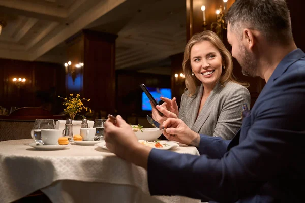 Ζευγάρι Γευματίζει Ατμοσφαιρικό Καφέ Χαρούμενη Γυναίκα Που Δείχνει Mobile App — Φωτογραφία Αρχείου