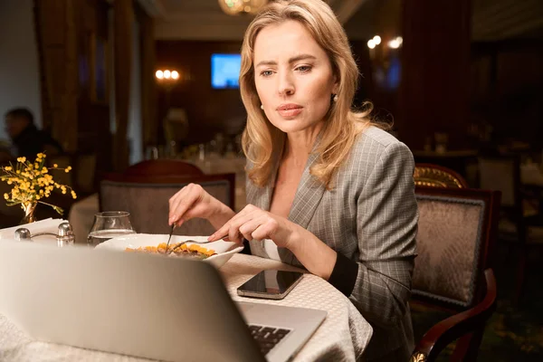 Koncenterad Affärskvinna Uppmärksamt Läsa Arbetsplan Laptop Att Äta Middag Restaurang — Stockfoto