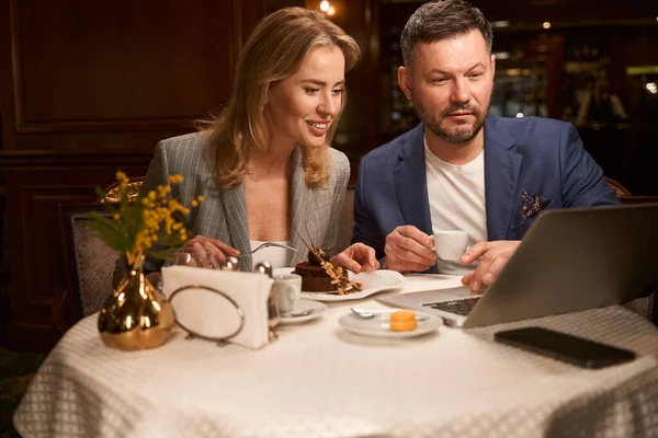 幸せな男と女楽しんで甘いデザートとコーヒーオン朝食見て最後のエピソードのお気に入りのシリーズのラップトップ — ストック写真