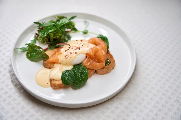 Delicious toast with smoked salmon and eggs benedict serving on plate, copy space