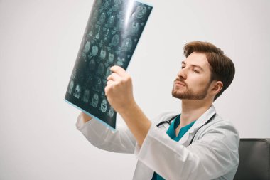 Erkek doktor, beyin MR 'ını dikkatlice inceler. Tıbbi üniformalı bir adam.