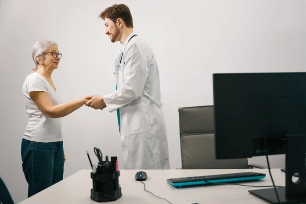 Artig Ung Läkare Hälsar Äldre Patient Man Medicinsk Uniform — Stockfoto
