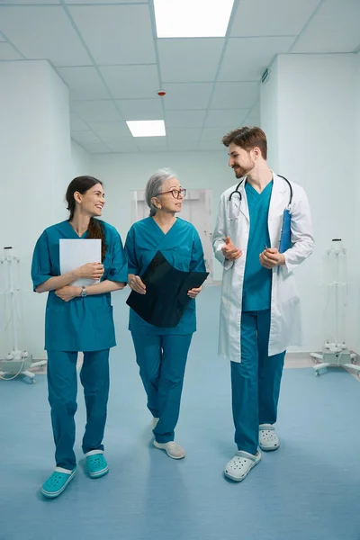 Muž Dvě Ženy Lékařských Uniformách Procházejí Nemocniční Chodbou Lékaři Komunikují — Stock fotografie