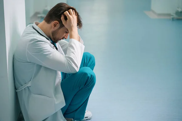 Traurige Junge Praktikantin Hockt Auf Krankenhausflur Mann Arztuniform — Stockfoto