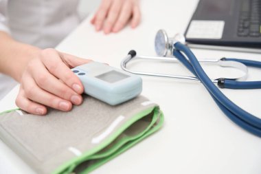 İşyerindeki doktor, tonometre ve steteskopla modern bir dizüstü bilgisayarın yanında.