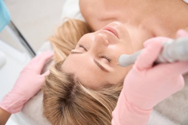 Lazer cilt yüzeyindeki kadın hasta prosedürü koruyucu eldivenli kadın CO2 lazer kullanıyor.