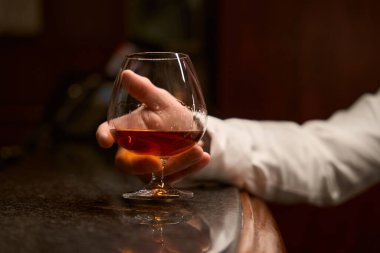 Bardaki resepsiyonda otururken erkek misafirin bir bardak brendi içmesini kapat.