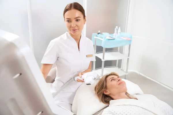 Qualified Cosmetologist Sets Apparatus Smas Lifting Patient Lies Couch Nearby — Stock Photo, Image