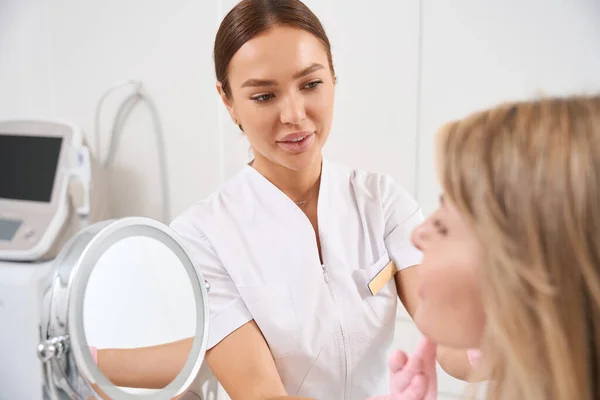 Médico Cosmetologista Examina Cliente Clínica Medicina Estética Mulher Olha Espelho — Fotografia de Stock