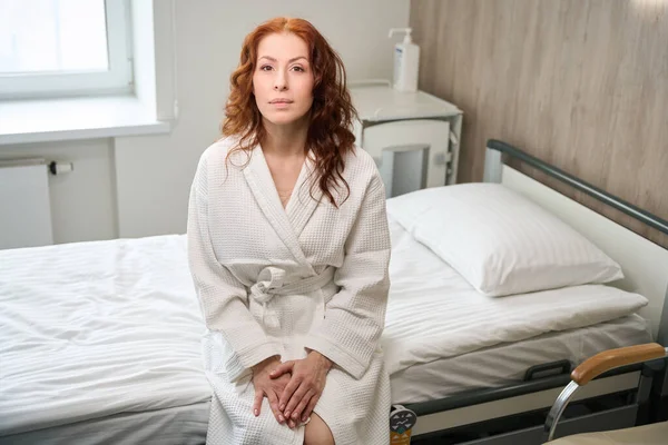现代医院病房 一位成熟的女病人坐在病床上 面对着摄像机 — 图库照片