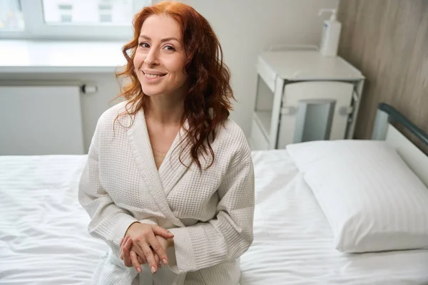 Glimlachende Vrouwelijke Patiënt Geconfronteerd Camera Terwijl Zitten Ziekbed Moderne Kamer — Stockfoto