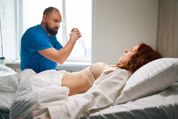 在现代保健中心 红头发女性访客躺在舒适的床上接受医生检查 — 图库照片