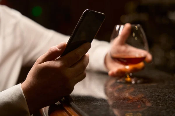 Nahaufnahme Einer Männlichen Hand Mit Telefon Und Einem Glas Brandy — Stockfoto