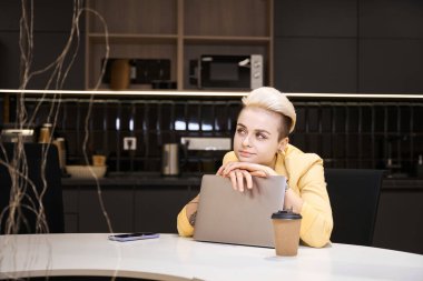 Hayalperest kadın ofis çalışanı dizüstü bilgisayarda çalışmak, oyalanmak ve ilham eksikliği yerine kafasını dizüstü bilgisayara dayayıp düşünüyor.